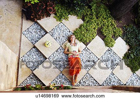 Stock Photo - High angle view of a mature woman lying in a garden. Fotosearch