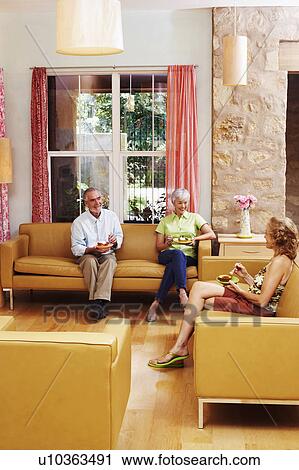 Stock Image - Mature couple and a senior woman sitting on a couch. Fotosearch