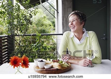 Picture - Mature woman holding a champagne flute and smiling. Fotosearch