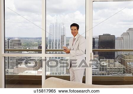 Stock Photography - Portrait of a businessman holding a personal data assistant. Fotosearch