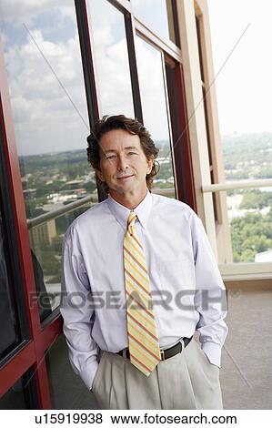 Portrait of a businessman leaning against a window View Large Photo Image Stock Photo - Portrait of a businessman leaning against a window. Fotosearch