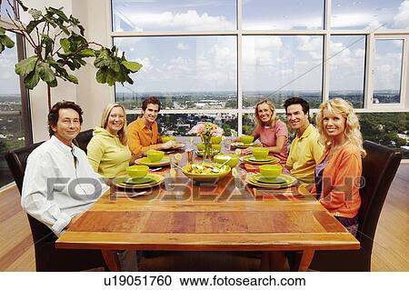 Stock Image - Portrait of a group of people sitting at a dining table. Fotosearch