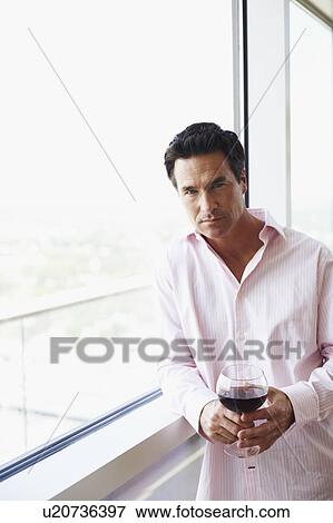 Stock Photo - Portrait of a mature man holding a glass of wine. Fotosearch