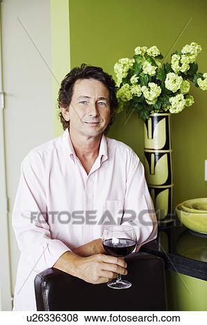 Stock Photo - Portrait of a mature man holding a glass of wine. Fotosearch