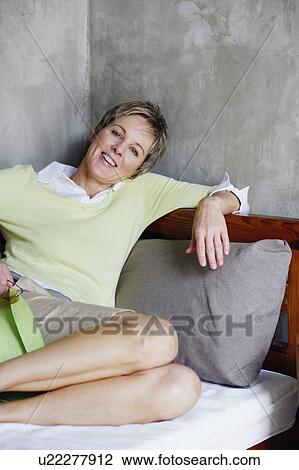 Portrait of a mature woman reclining on the bed and smiling View Large Photo Image Stock Image - Portrait of a mature woman reclining on the bed and smiling. Fotosearch