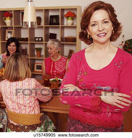 Portrait of a mature woman smiling and her friends sitting at the dining table in the background View Large Photo Image Stock Photography - Portrait of a mature woman smiling and her friends sitting at the dining table in the background. Fotosearch