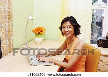 Stock Photo - Portrait of a mature woman using a laptop and smiling. Fotosearch