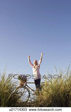 Low angle view of a mature woman standing with her arms raised View Large Photo Image Stock Image - Low angle view of a mature woman standing with her arms raised. Fotosearch