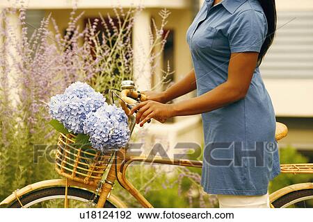 Stock Image - Mid section view of a woman standing with a bicycle. Fotosearch