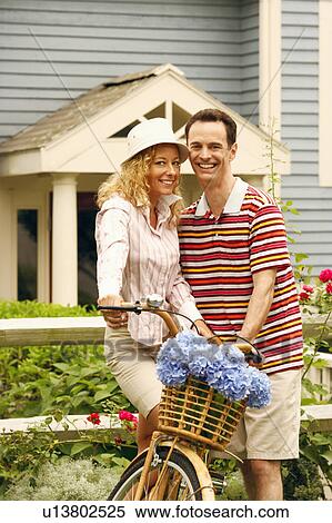 Stock Photography - Portrait of a mature couple standing with a bicycle and smiling. Fotosearch