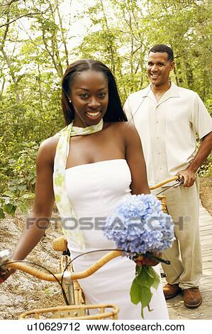 Stock Image - Portrait of a mid adult woman smiling with a mature man standing behind her. Fotosearch