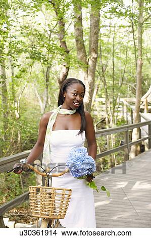 Picture - Portrait of a mid adult woman standing with a bicycle. Fotosearch