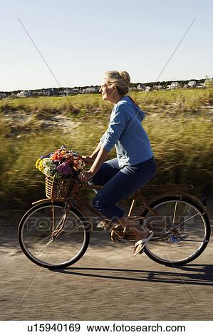 Stock Photo - Side profile of a mature woman riding a bicycle. Fotosearch