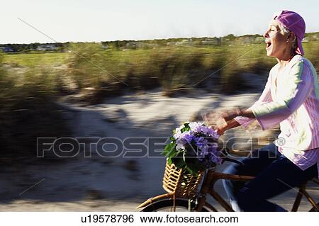 Stock Photograph - Side profile of a mature woman riding a bicycle. Fotosearch