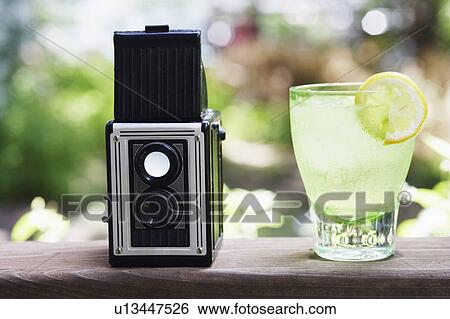 Stock Photograph - Close-up of a camera and a glass of lemonade. Fotosearch