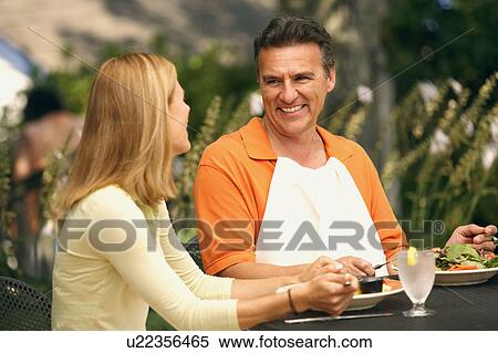 Close-up of a mature man and a mid adult woman sitting at the table and smiling View Large Photo Image Stock Photography - Close-up of a mature man and a mid adult woman sitting at the table and smiling. Fotosearch