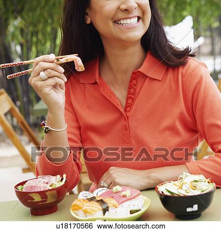 Stock Photograph - Close-up of a mature woman eating with chopsticks. Fotosearch