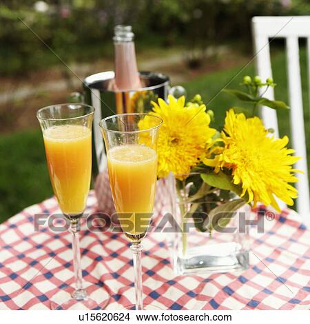 Picture - Close-up of two glasses of juice with a flower vase and an ice bucket on the table. Fotosearch