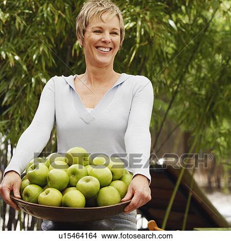 Mature woman holding a bowl of apples View Large Photo Image Picture - Mature woman holding a bowl of apples. Fotosearch