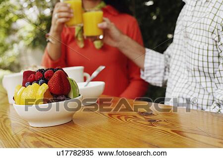 Stock Photography - Mid section view of a couple toasting glasses of orange juice. Fotosearch