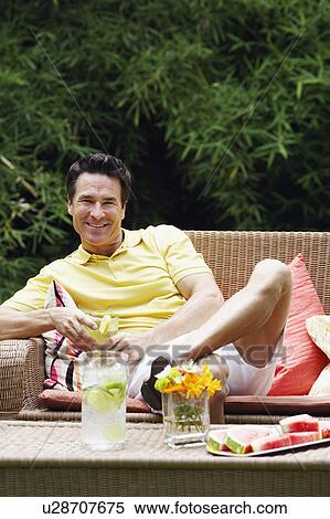 Stock Photography - Portrait of a mature man sitting on a couch and smiling. Fotosearch