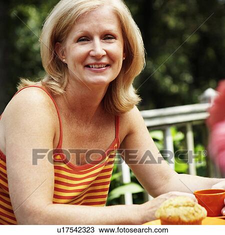 Portrait of a mature woman sitting at the table and holding a cup View Large Photo Image Stock Image - Portrait of a mature woman sitting at the table and holding a cup. Fotosearch