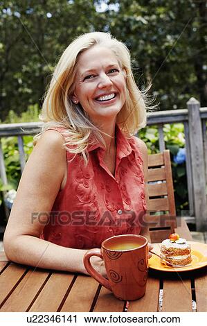 Portrait of a mature woman sitting with a plate of dessert in front of her and smiling View Large Photo Image Stock Image - Portrait of a mature woman sitting with a plate of dessert in front of her and smiling. Fotosearch