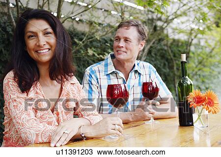 Close-up of a mature couple holding glasses of wine and smiling View Large Photo Image Stock Image - Close-up of a mature couple holding glasses of wine and smiling. Fotosearch