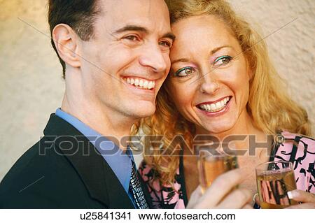 Close-up of a mature couple holding glasses of champagne and smiling View Large Photo Image Stock Image - Close-up of a mature couple holding glasses of champagne and smiling. Fotosearch