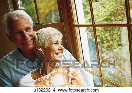 Close-up of a senior woman wearing headphones and smiling with a mature man View Large Photo Image Picture - Close-up of a senior woman wearing headphones and smiling with a mature man. Fotosearch