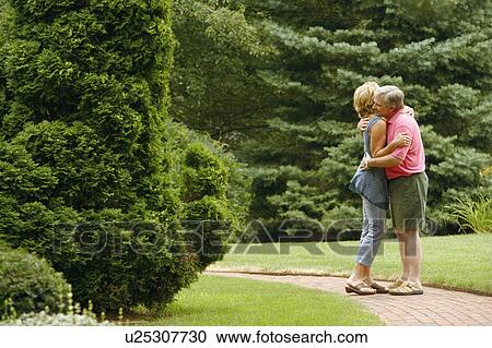 Stock Image - Mature couple embracing each other in a park. Fotosearch