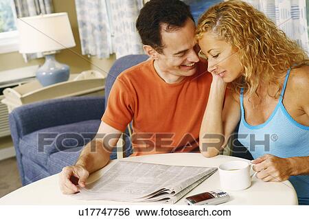 Stock Photograph - Mature couple sitting together at the table and smiling. Fotosearch