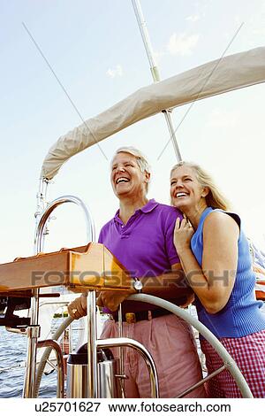 Mature couple standing in a boat and smiling View Large Photo Image Stock Photo - Mature couple standing in a boat and smiling. Fotosearch