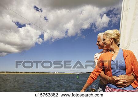 Mature man embracing a mature woman from behind in a sailboat and smiling View Large Photo Image Stock Image - Mature man embracing a mature woman from behind in a sailboat and smiling. Fotosearch