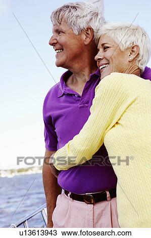Stock Image - Mature woman embracing a mature man in a boat and smiling together. Fotosearch