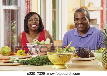 Stock Photo - Portrait of a mature couple cutting vegetables and smiling. Fotosearch