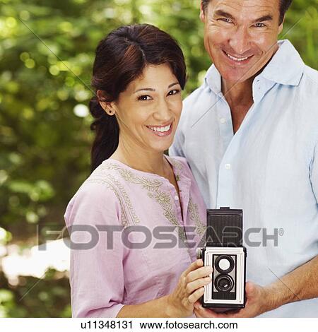 Portrait of a mature couple holding a camera View Large Photo Image Stock Image - Portrait of a mature couple holding a camera. Fotosearch