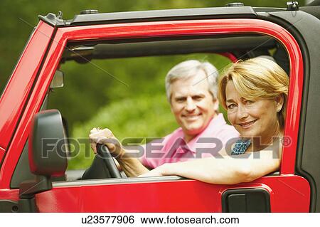 Stock Photograph - Portrait of a mature couple in a sports utility vehicle and smiling. Fotosearch