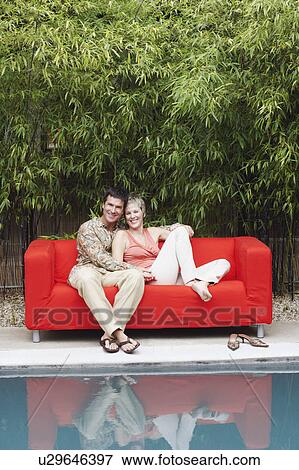 Portrait of a mature couple sitting on a couch and smiling View Large Photo Image Stock Photo - Portrait of a mature couple sitting on a couch and smiling. Fotosearch