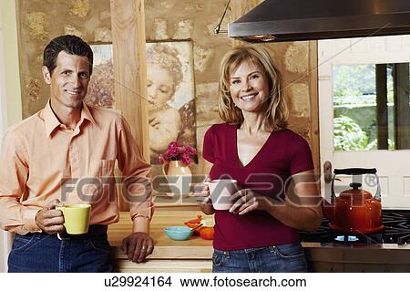 Picture - Portrait of a mature couple smiling and holding cups. Fotosearch