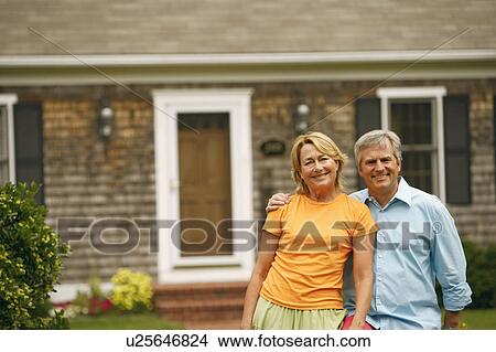 Portrait of a mature couple standing in front of a house View Large Photo Image Picture - Portrait of a mature couple standing in front of a house. Fotosearch