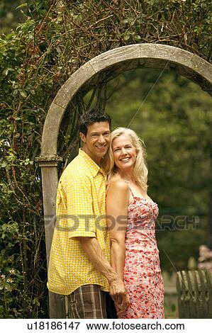 Stock Photo - Portrait of a mature couple standing in a park and smiling. Fotosearch