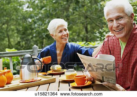 Picture - Portrait of a mature man and a senior woman sitting at the table and smiling. Fotosearch