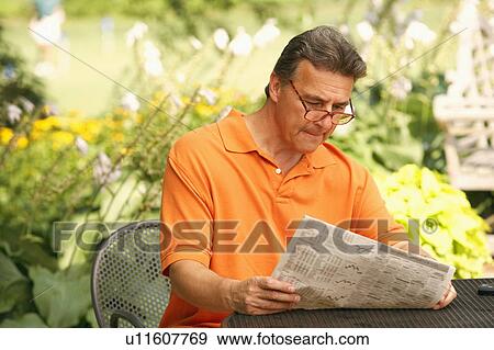 Close-up of a mature man reading a newspaper in a park View Large Photo Image Stock Photo - Close-up of a mature man reading a newspaper in a park. Fotosearch