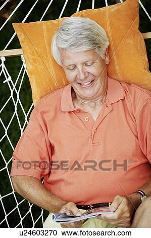 High angle view of a mature man lying in a hammock and reading a magazine View Large Photo Image Stock Image - High angle view of a mature man lying in a hammock and reading a magazine. Fotosearch