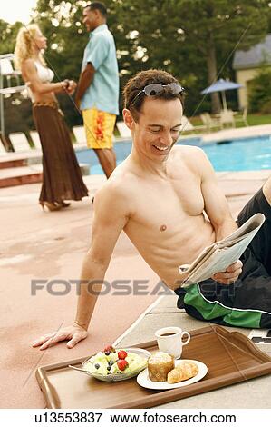 Mature man reading a newspaper at the poolside View Large Photo Image Stock Photo - Mature man reading a newspaper at the poolside. Fotosearch