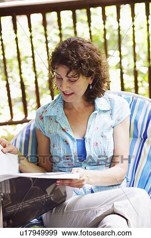 Mature woman reading a newspaper View Large Photo Image Stock Photo - Mature woman reading a newspaper. Fotosearch