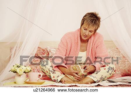 Mature woman sitting on the bed and reading a book View Large Photo Image Stock Photograph - Mature woman sitting on the bed and reading a book. Fotosearch