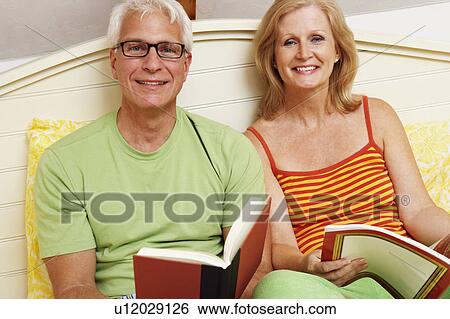 Portrait of a mature couple sitting on the bed and smiling View Large Photo Image Stock Photograph - Portrait of a mature couple sitting on the bed and smiling. Fotosearch