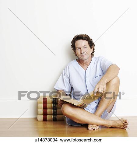 Picture - Portrait of a mature man sitting on the floor and holding a book. Fotosearch
